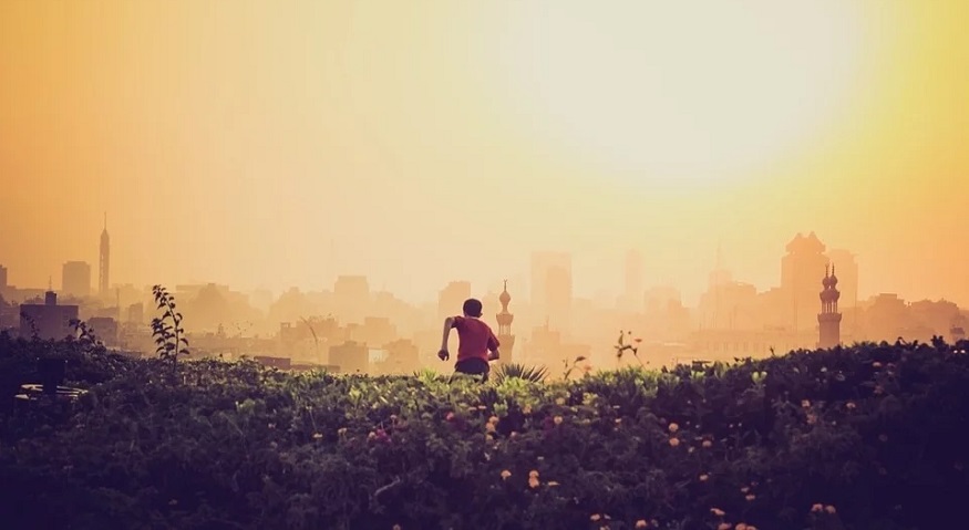 India air pollution - boy running toward smoggy city in India