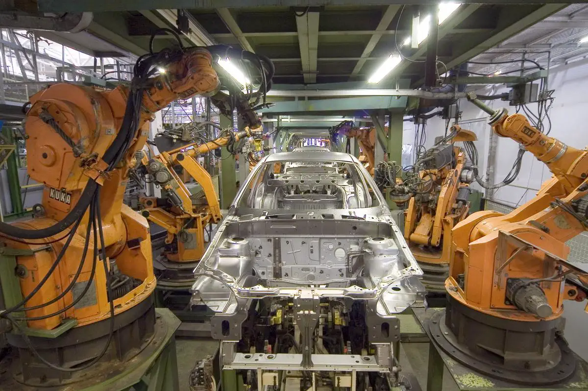 A modern Ford electric vehicle production line with workers and robots assembling cars